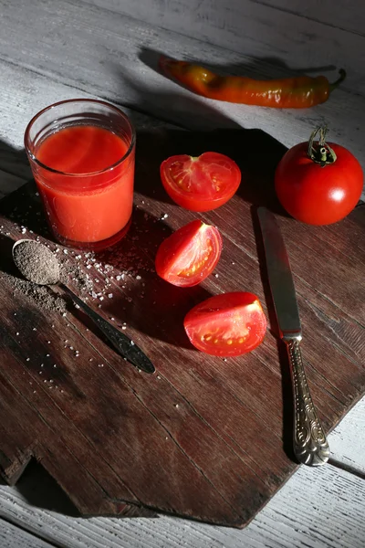 Pahar de suc de roșii cu condimente și roșii proaspete pe masa de lemn. Cu fundal întunecat — Fotografie, imagine de stoc