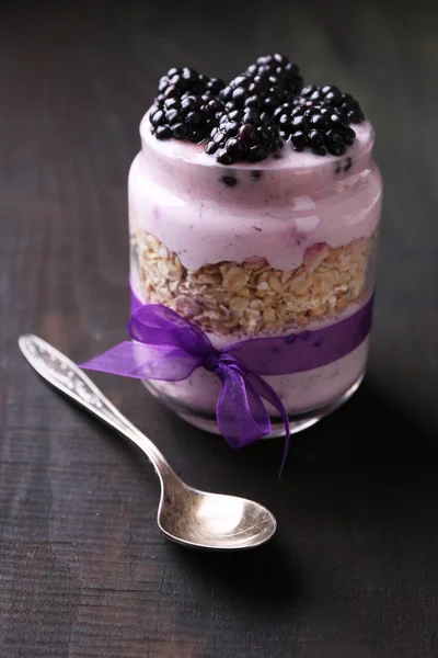 Gezond ontbijt - yoghurt met bramen en muesli geserveerd in glazen pot, op donkere houten achtergrond — Stockfoto