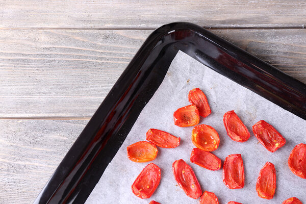 Sun dried tomatoes on drying tray, on wooden background