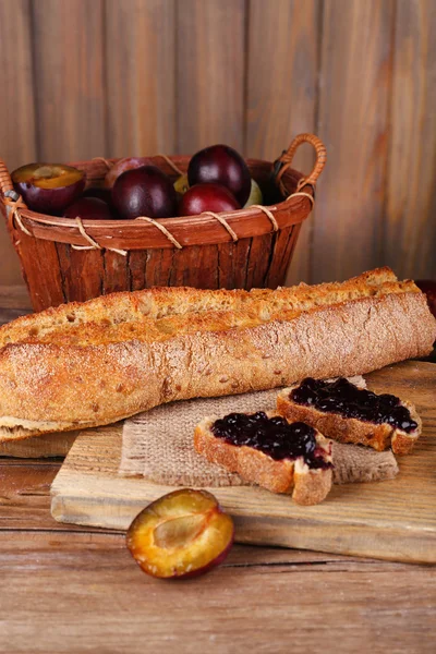 Bröd med plommon sylt på träbord närbild — Stockfoto