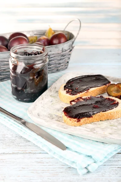 Bread with plum jam and plums on wooden table — Stock Photo, Image