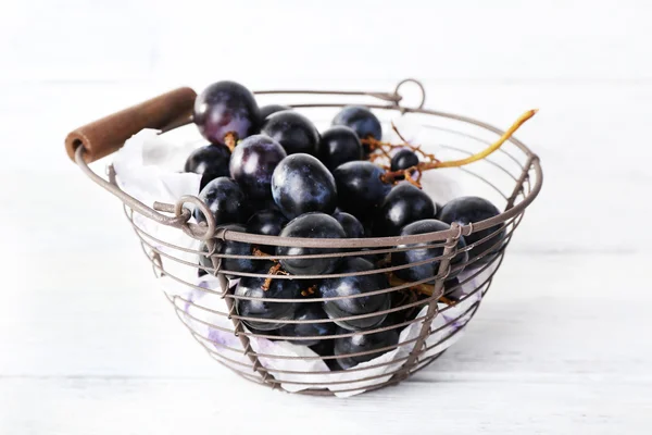 Purple grapes in basket on wooden background — Stock Photo, Image