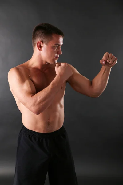 Handsome young muscular sportsman boxing on dark background — Stock Photo, Image