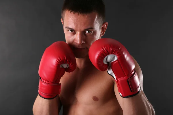 英俊年轻肌肉型男用拳击手套在深色背景上 — 图库照片