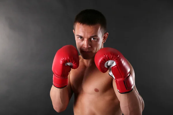 Guapo joven deportista muscular con guantes de boxeo sobre fondo oscuro —  Fotos de Stock