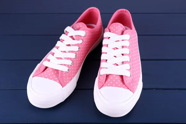 Pink trainers on dark blue wooden background — Stock Photo, Image
