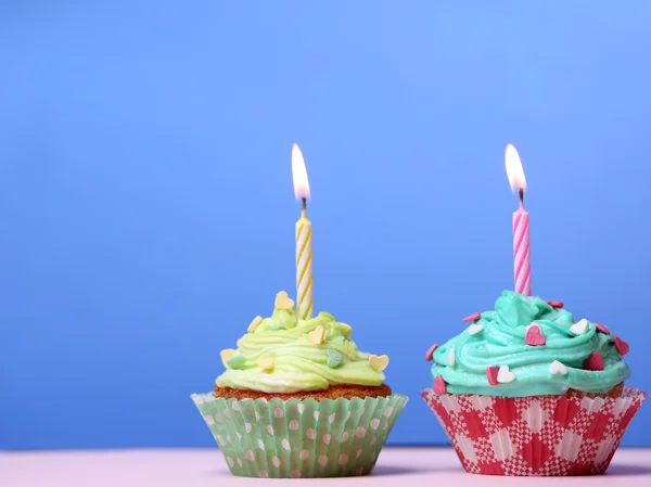 Heerlijke verjaardag cupcakes op tafel op blauwe achtergrond — Stockfoto