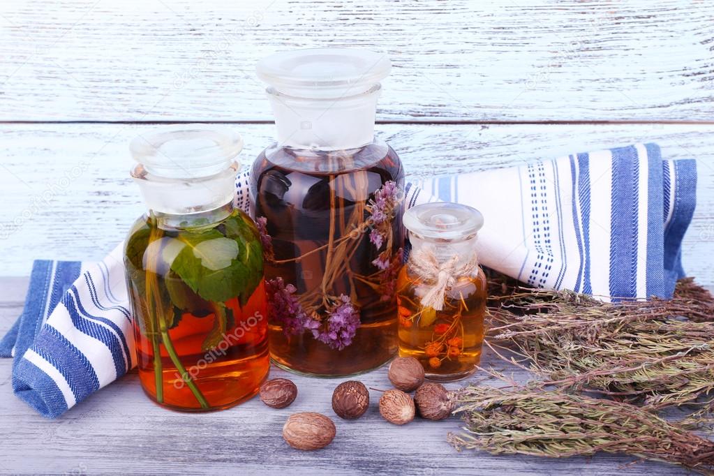 Bottles of herbal tincture and dried leaves on wooden background
