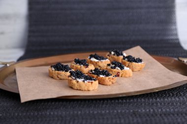 tereyağı ve kağıt tepsisindeki kumaş arka plan üzerinde siyah havyar ile ekmek dilimleri