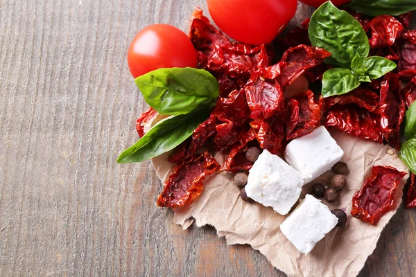 Sun dried and fresh tomatoes, basil leaves and feta cheese on color wooden background — Stock Photo, Image