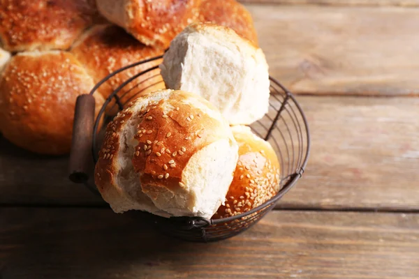 Pães saborosos com gergelim na cor de fundo de madeira — Fotografia de Stock