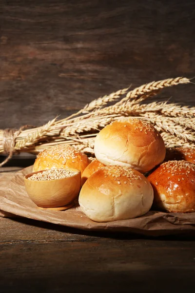 Tasty buns with sesame on wooden background — Stock Photo, Image