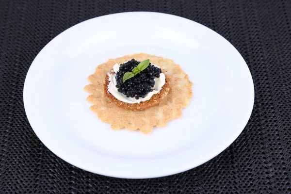 Caviar negro con pan crujiente en plato sobre fondo de tela oscura — Foto de Stock