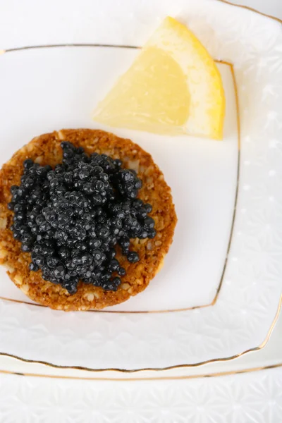 Black caviar on crispy bread on plate closeup — Stock Photo, Image