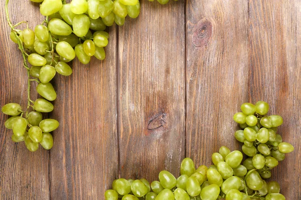 Куча спелого винограда на коричневом деревянном фоне — стоковое фото