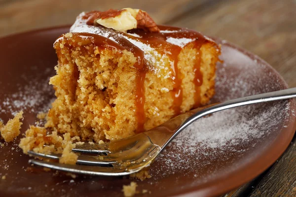 Half eaten delicious cake piece on plate on wooden table — Stock Photo, Image