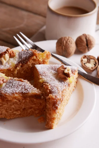 Pezzi di torta deliziosa con noci sul piatto sul tavolo di legno — Foto Stock