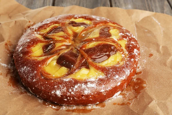 Leckerer Kuchen mit Karamell auf Papier auf dem Tisch aus nächster Nähe — Stockfoto