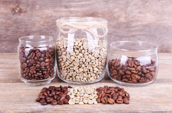 Coffee in glass jars on wooden background — Stock Photo, Image