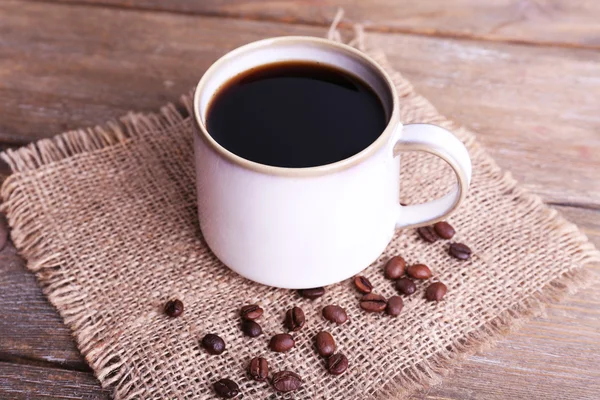 Taza de café sobre tela de saco sobre fondo de madera — Foto de Stock