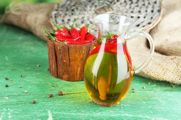 Zelfgemaakte natuurlijke geïnfundeerd olijfolie met rode chilipepertjes op een houten achtergrond kleur — Stockfoto