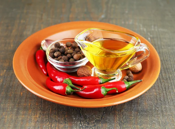 Set of spices and olive oil on plate, on  wooden background — Stock Photo, Image