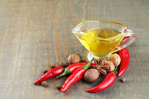 Zelfgemaakte natuurlijke doordrenkt olijfolie met rode chilipepertjes en specerijen op houten achtergrond — Stockfoto