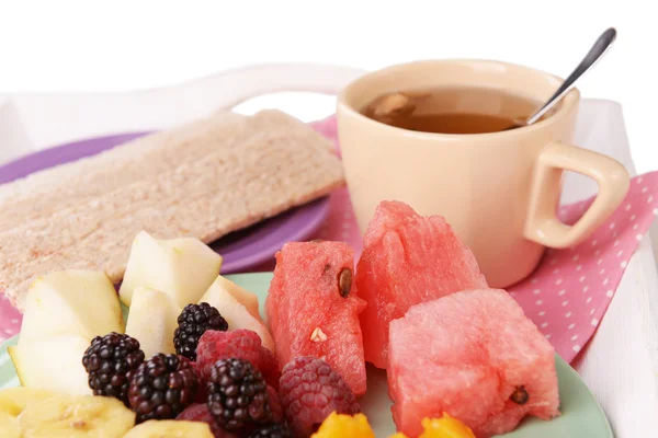 Rebanadas de frutas con pan crujiente en el plato y taza de té en bandeja de madera de cerca — Foto de Stock