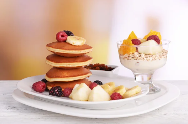 Pancake with fruits on plate and muesli on table on bright background — Stock Photo, Image