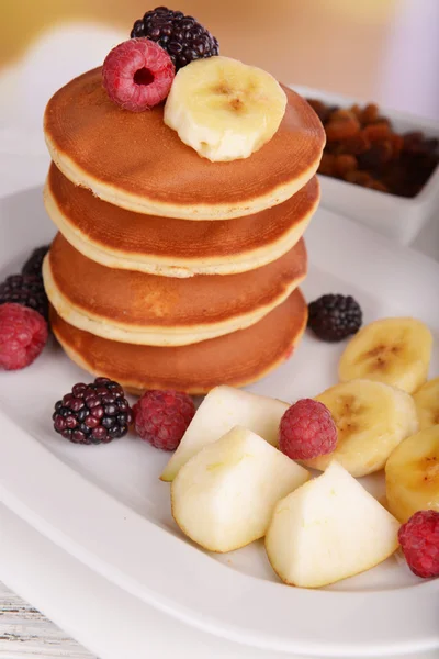 Pfannkuchen mit Früchten und Beeren auf dem Tisch vor hellem Hintergrund — Stockfoto