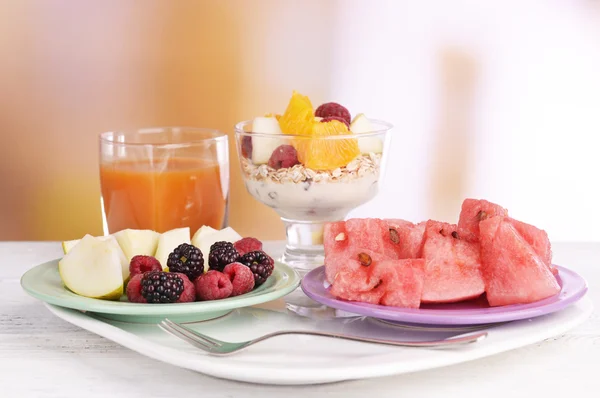 Rebanadas de frutas con bayas y muesli en la mesa sobre fondo brillante —  Fotos de Stock