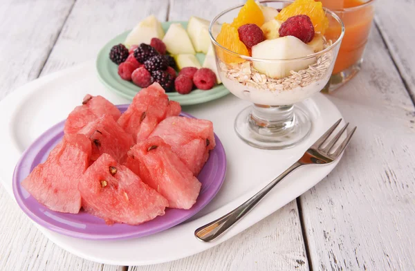 Segmenten van vruchten met bessen en muesli op houten tafel — Stockfoto