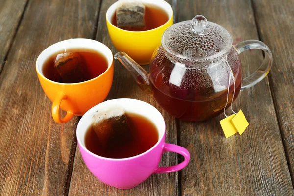 Tazas de té, tetera y bolsitas de té en la mesa de madera de cerca — Foto de Stock