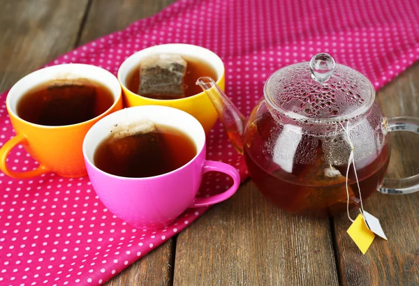 Tazas de té, tetera y bolsitas de té en la mesa de madera de cerca —  Fotos de Stock