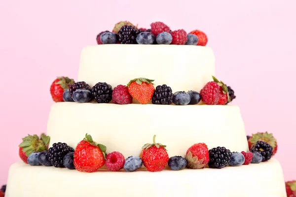 Красивый свадебный торт с ягодами на розовом фоне — стоковое фото