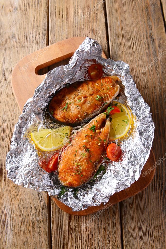 Tasty baked fish in foil on table close-up — Stock Photo © belchonock