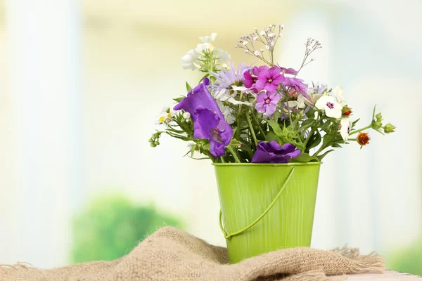 Ramo de flores de colores en jarrón decorativo, sobre la mesa, sobre fondo brillante — Foto de Stock