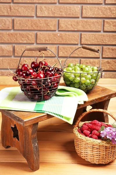 Frische Beeren in Körben auf Wandhintergrund — Stockfoto