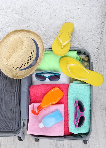 Mala com coisas no tapete branco no chão para viajar para algum lugar perto da água para passar férias de verão — Fotografia de Stock