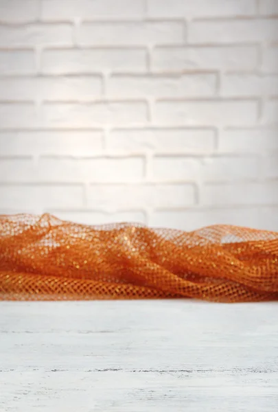 Wooden table with cloth on wall background