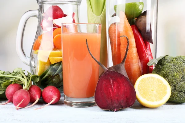 Jar of cut vegetables and glass of fresh carrot juice with vegetables on wooden table