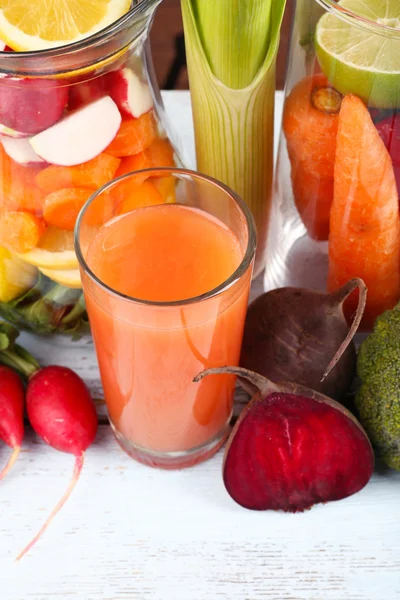 Банка нарезанных овощей и стакан свежего морковного сока с овощами на деревянном столе — стоковое фото