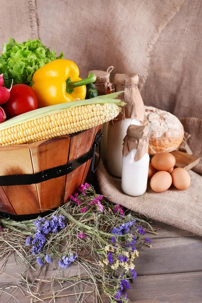 Grande cesta de madeira redonda com legumes, leite e pão no fundo de saque — Fotografia de Stock
