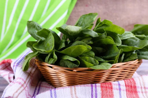 Sorrel fresco in cesto di vimini rotondo su tovagliolo su sfondo di legno — Foto Stock