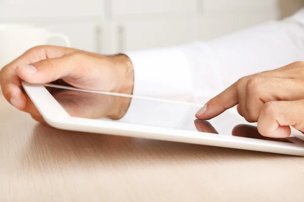 Hombre trabajando en la tableta sobre fondo de madera primer plano — Foto de Stock