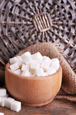 Tablo arka plan üzerinde rafine şeker ahşap kase