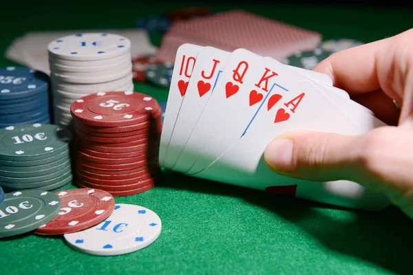 Chips en kaarten voor poker in de hand op groene tabel — Stockfoto