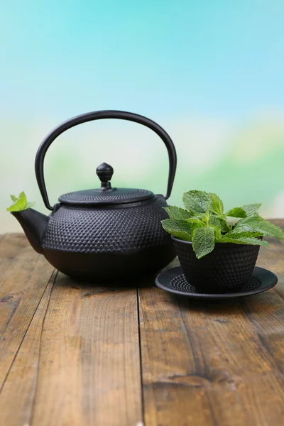 中国传统茶壶配新鲜的薄荷叶在木桌前，在明亮的背景上 — 图库照片