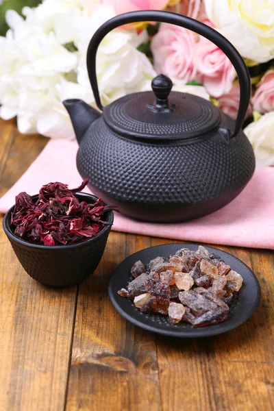 Tetera negra, tazón y té de hibisco en la mesa de madera de color, sobre fondo brillante —  Fotos de Stock