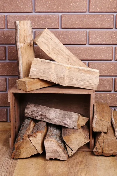 Caja de madera de leña en el suelo sobre fondo de ladrillo — Foto de Stock